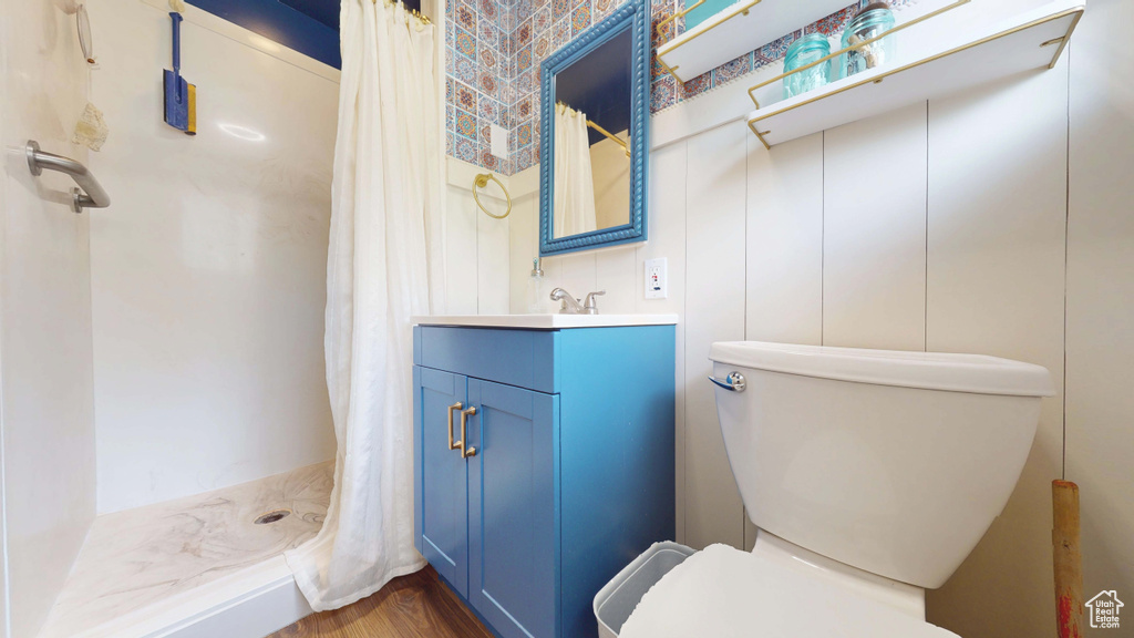Bathroom featuring toilet, vanity, curtained shower, and wood finished floors