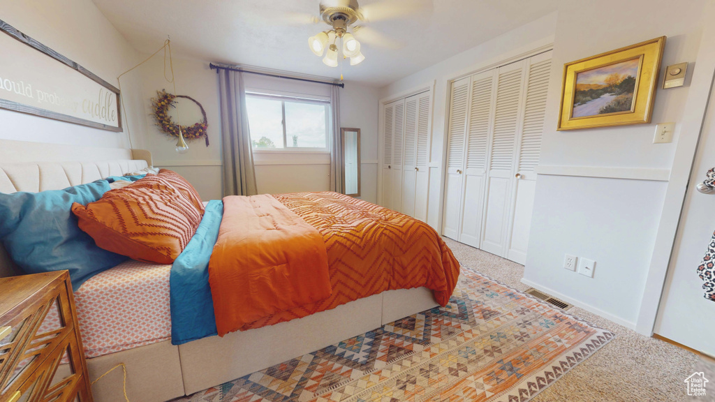 Carpeted bedroom featuring multiple closets, a ceiling fan, and baseboards