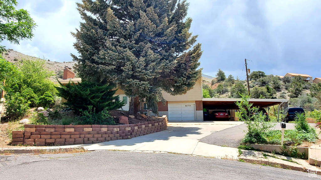 Obstructed view of property with an attached garage, driveway, and a carport