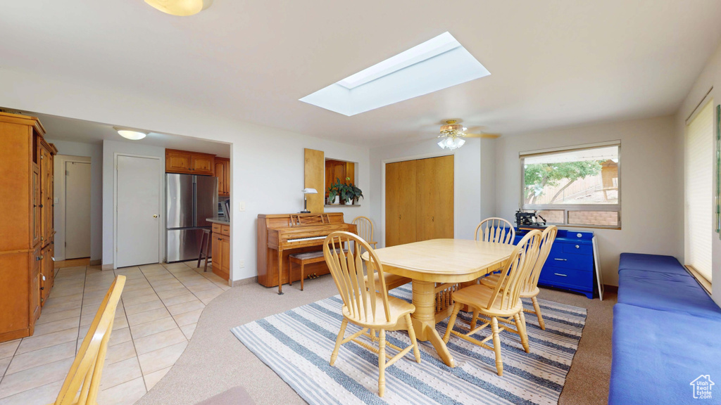Dining space with a skylight, light tile patterned flooring, and baseboards