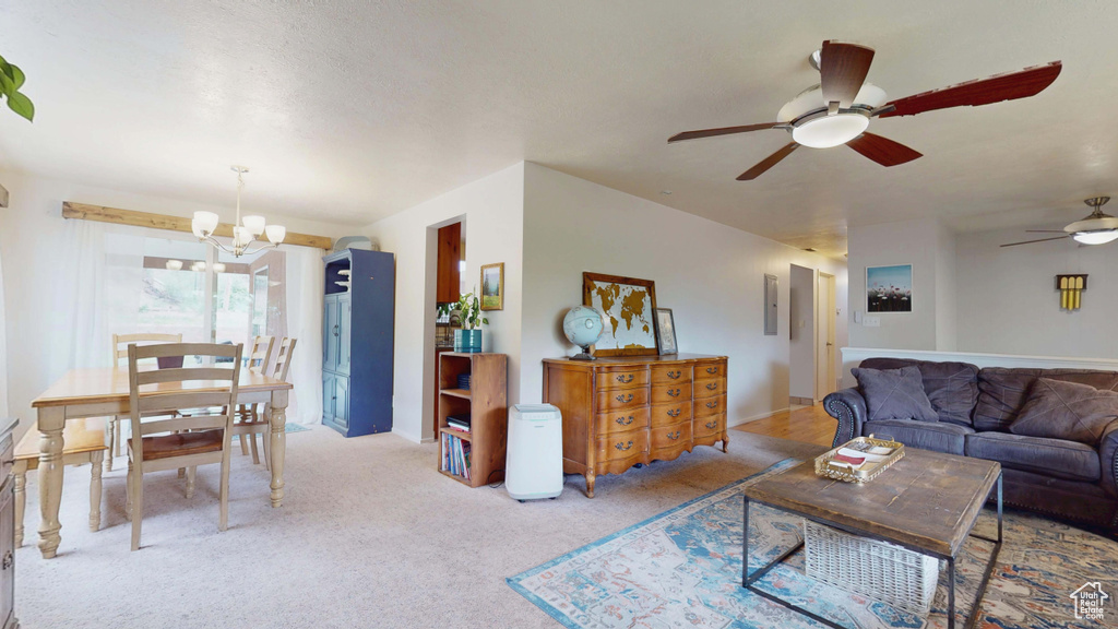 Living room featuring a chandelier, ceiling fan, and carpet flooring