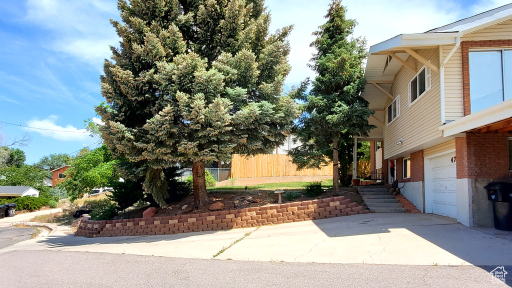 View of property exterior featuring a garage, driveway, and brick siding