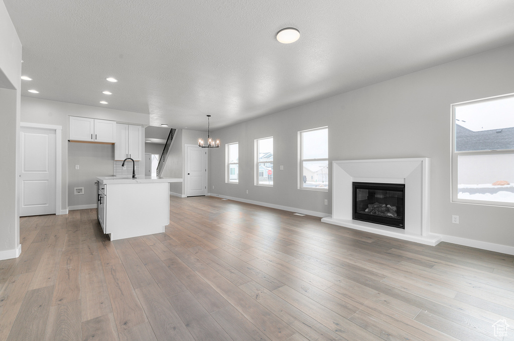 Kitchen featuring a chandelier, open floor plan, light countertops, baseboards, and recessed lighting