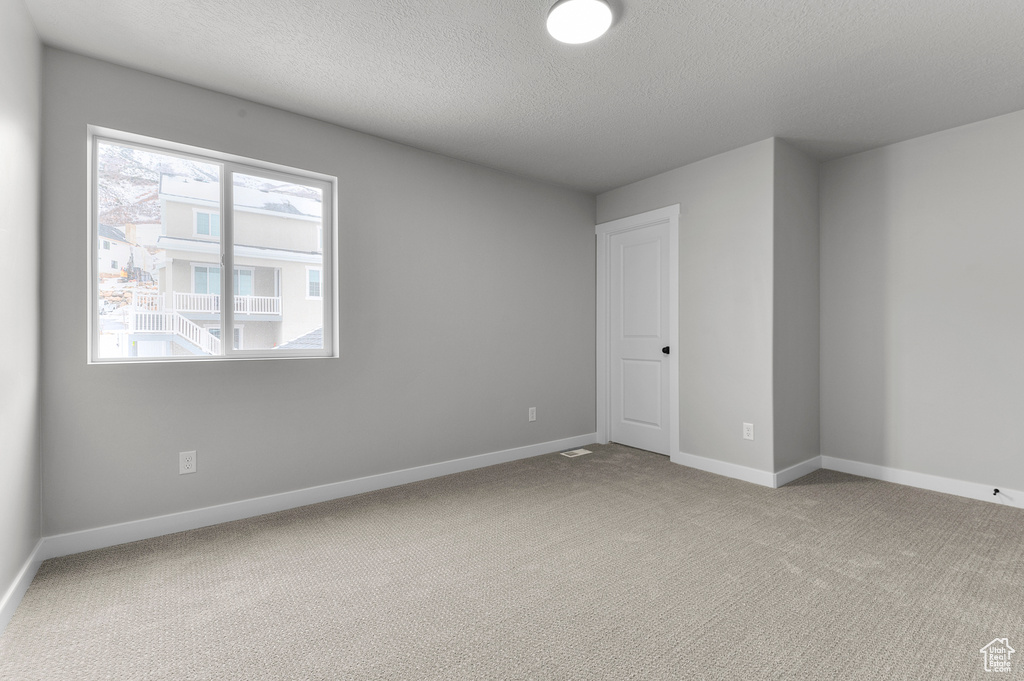 Carpeted spare room featuring baseboards and a textured ceiling