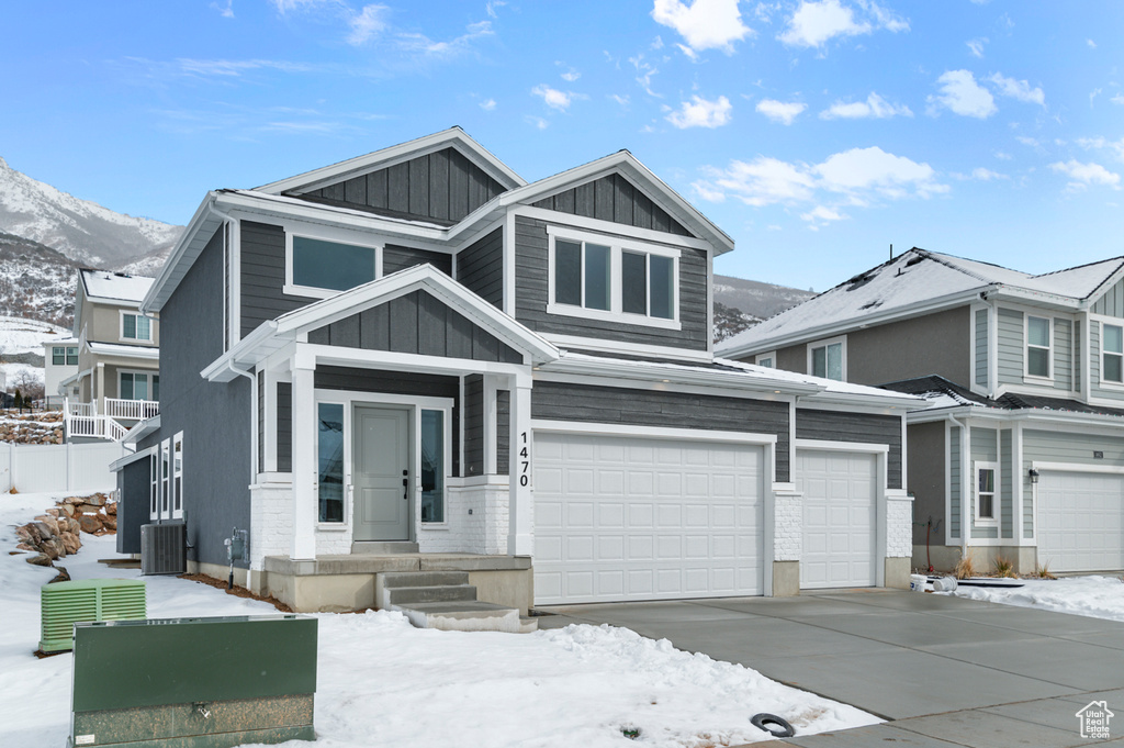 View of front of home featuring board and batten siding, a mountain view, cooling unit, concrete driveway, and a garage