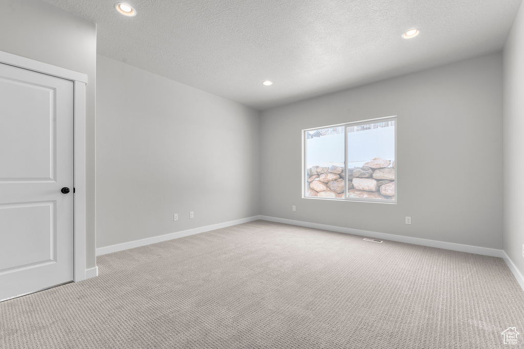 Spare room with light colored carpet, recessed lighting, baseboards, and a textured ceiling