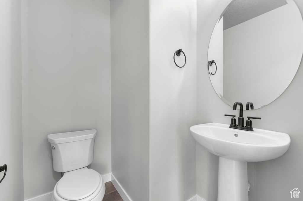 Bathroom with toilet, baseboards, and wood finished floors