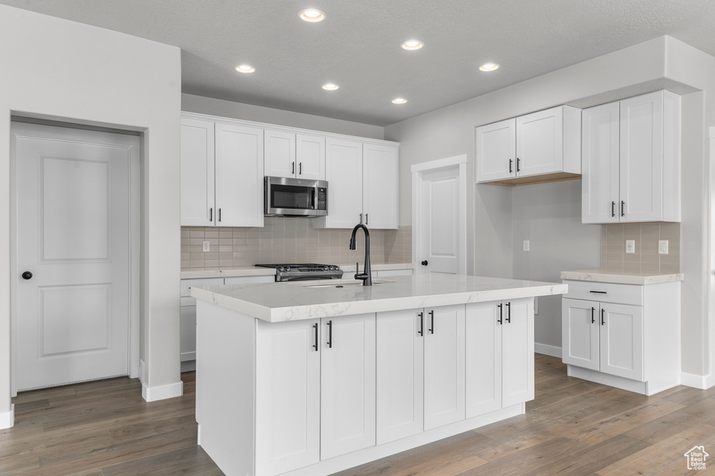 Kitchen featuring appliances with stainless steel finishes, a sink, decorative backsplash, recessed lighting, and white cabinets