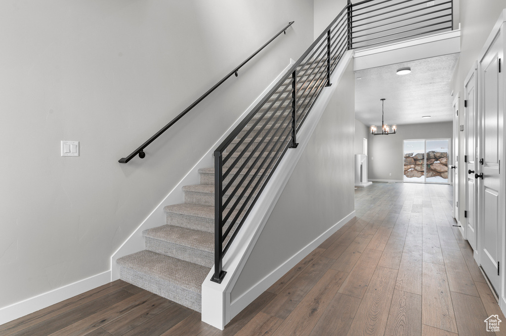 Stairway featuring a chandelier, hardwood / wood-style floors, and baseboards
