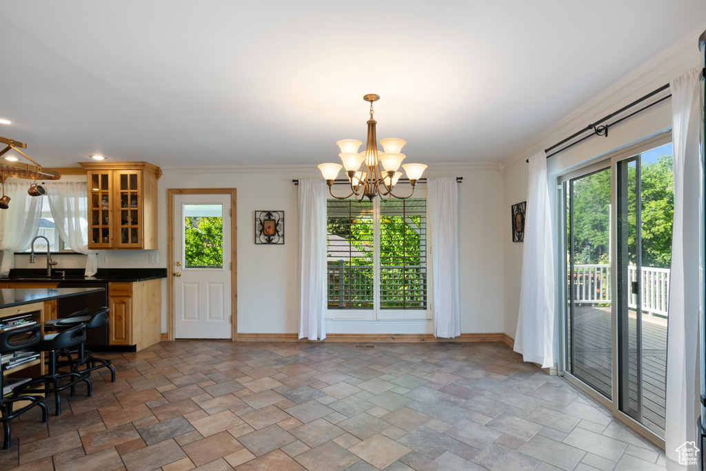 Kitchen featuring stone finish floors, dark countertops, baseboards, healthy amount of natural light, and crown molding