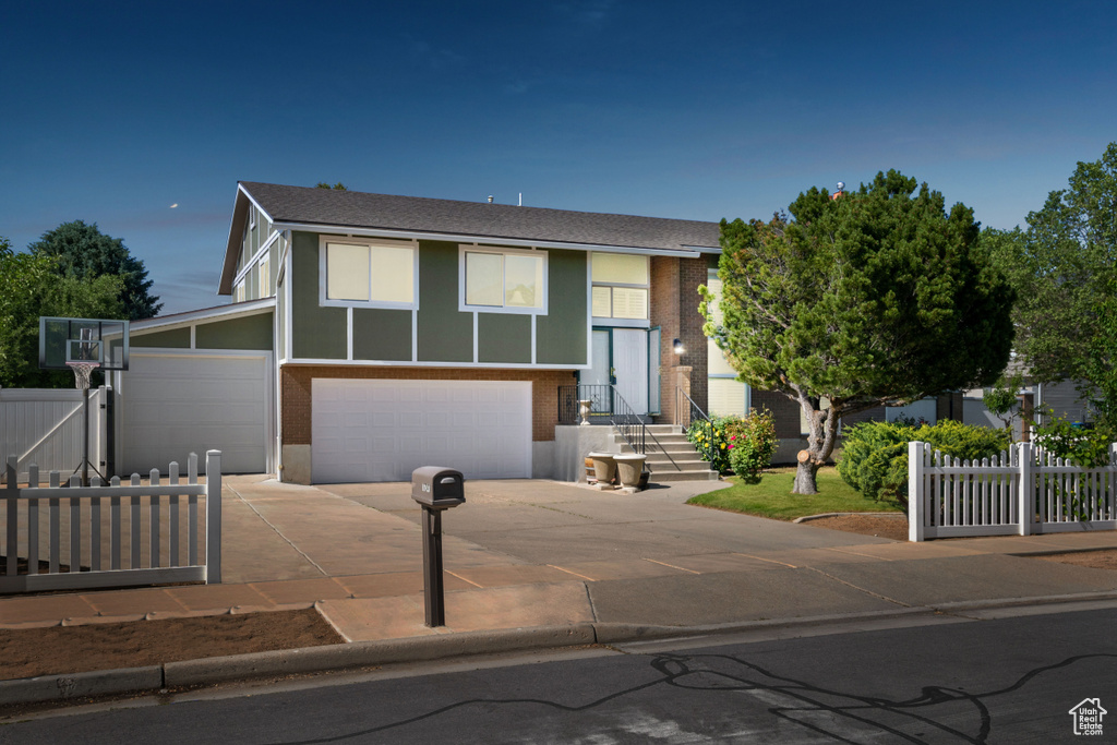 Bi-level home with concrete driveway, a garage, and a shingled roof