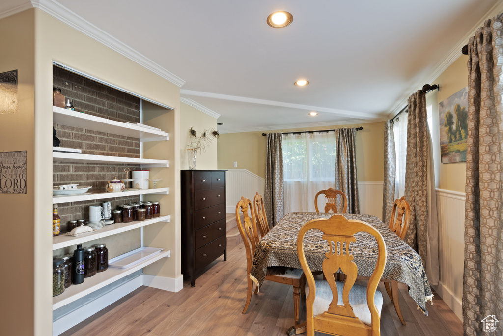 Dining space with crown molding, wood finished floors, recessed lighting, and a wainscoted wall