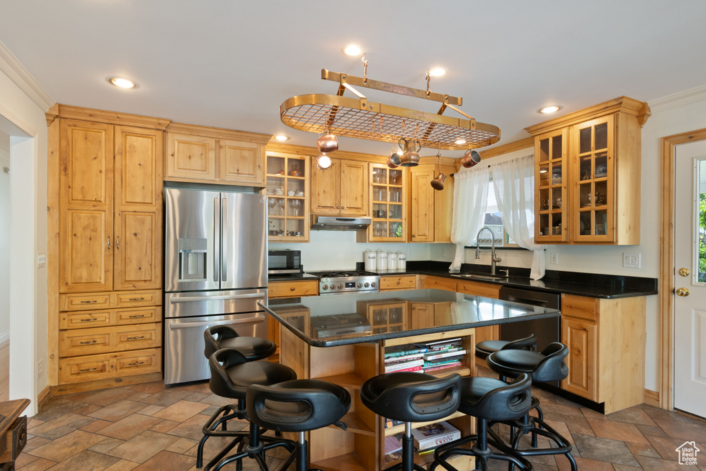 Kitchen featuring stainless steel appliances, a sink, under cabinet range hood, stone tile floors, and crown molding