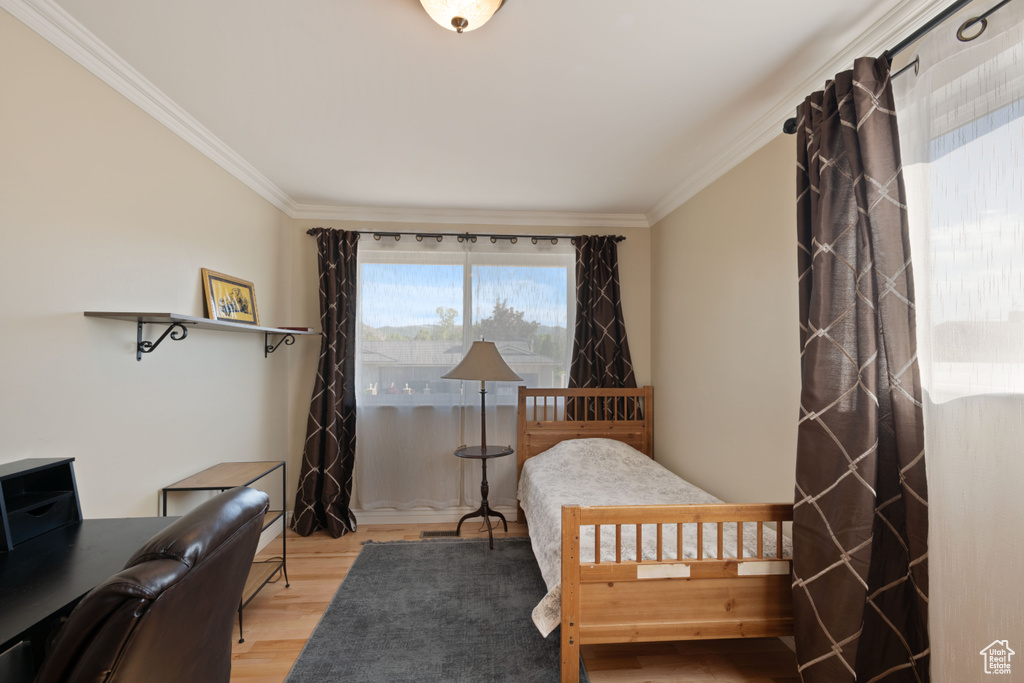 Bedroom with wood finished floors, crown molding, and an office area