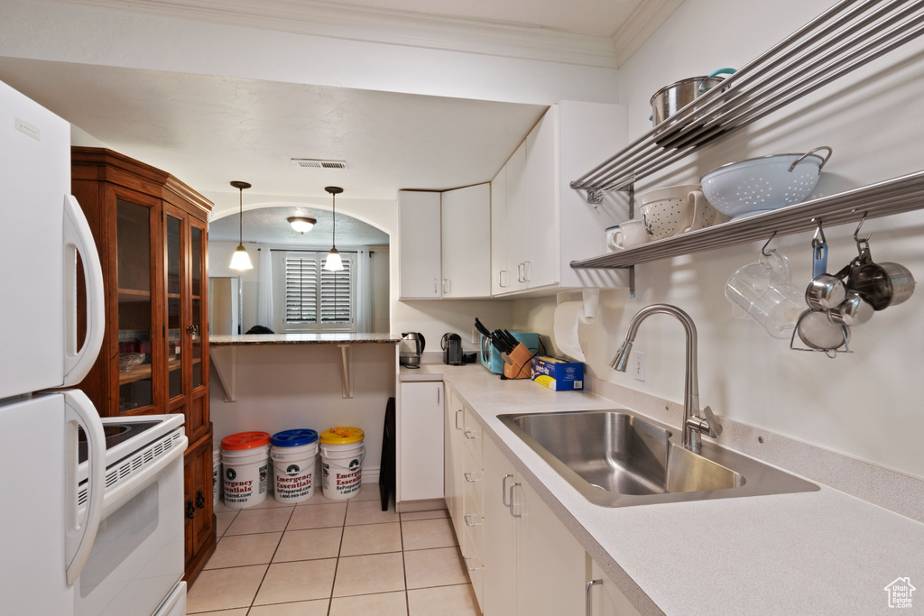 Kitchen with white appliances, a sink, open shelves, light tile patterned floors, and white cabinets