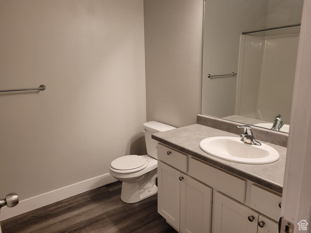 Bathroom featuring vanity, wood finished floors, toilet, and baseboards