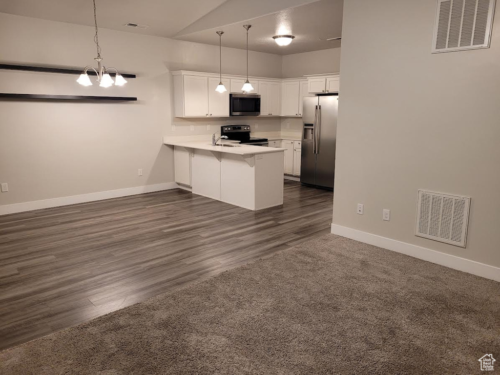 Kitchen with appliances with stainless steel finishes, a peninsula, a breakfast bar, light countertops, and white cabinets