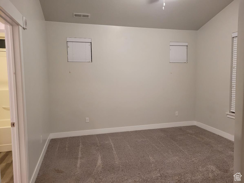 Empty room with dark colored carpet and baseboards