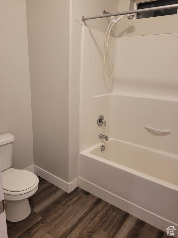 Full bath with toilet, tub / shower combination, wood finished floors, and baseboards