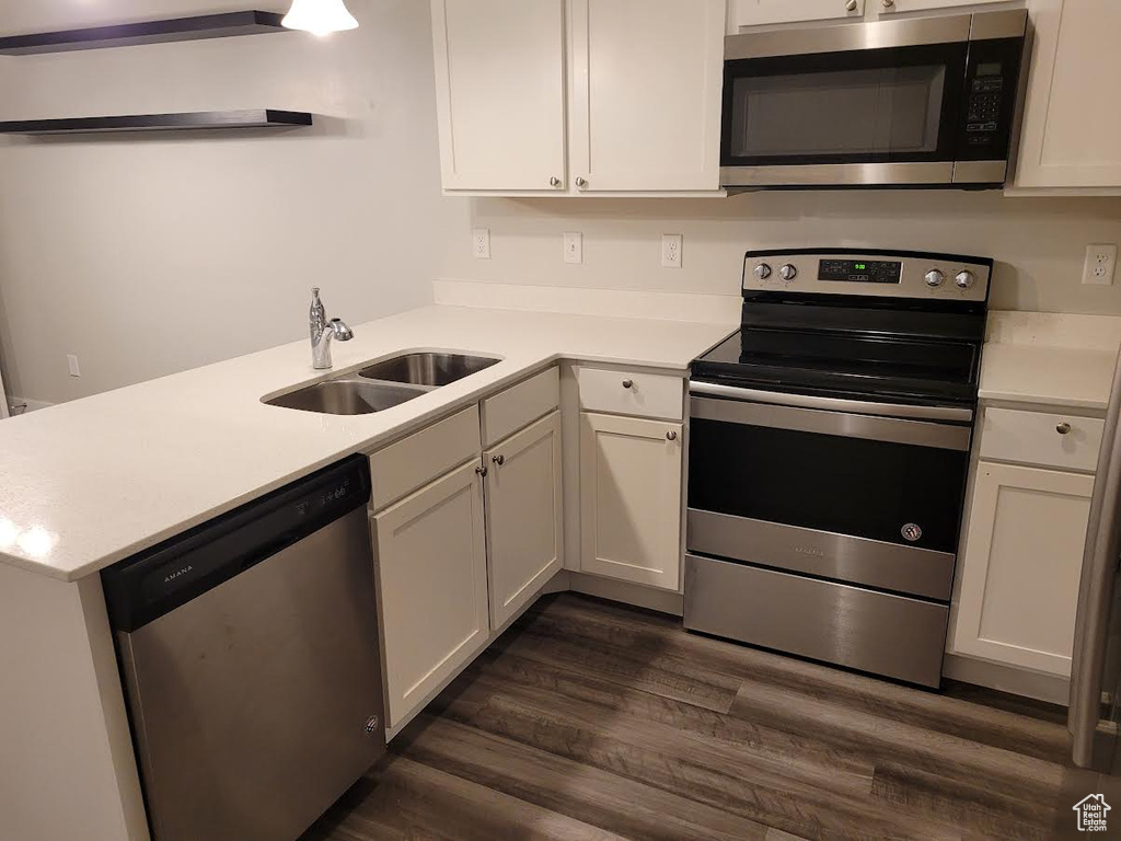 Kitchen featuring stainless steel appliances, a sink, light countertops, and dark wood-style flooring