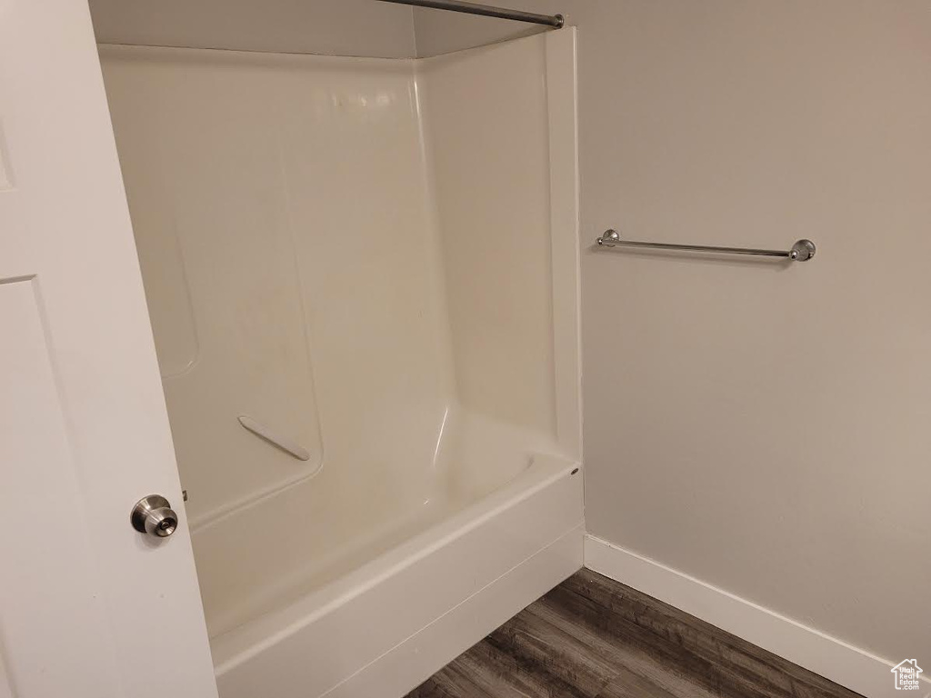Full bath featuring wood finished floors, baseboards, and shower / washtub combination