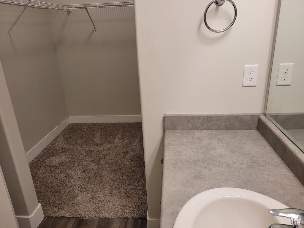 Bathroom featuring a walk in closet, a sink, and baseboards