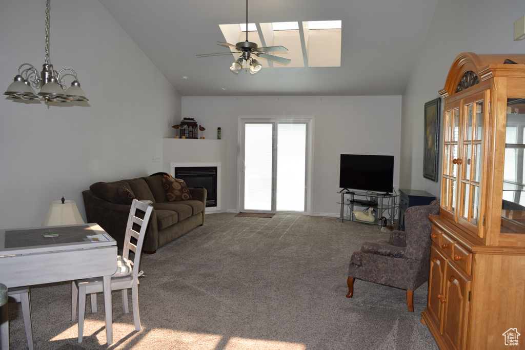 Carpeted living room featuring lofted ceiling, a glass covered fireplace, ceiling fan, and a chandelier