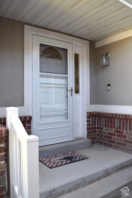 Property entrance with covered porch and stucco siding
