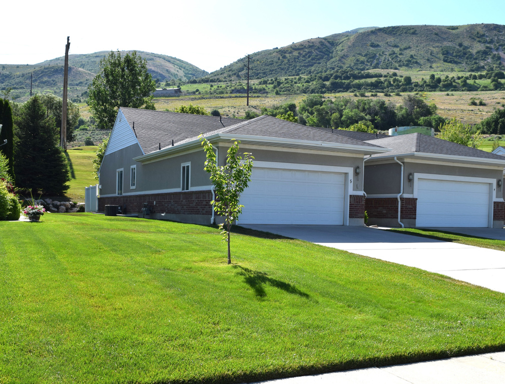 View of front of property with brick siding, a mountain view, an attached garage, and a front yard