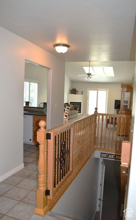 Stairs with ceiling fan, healthy amount of natural light, a glass covered fireplace, and baseboards