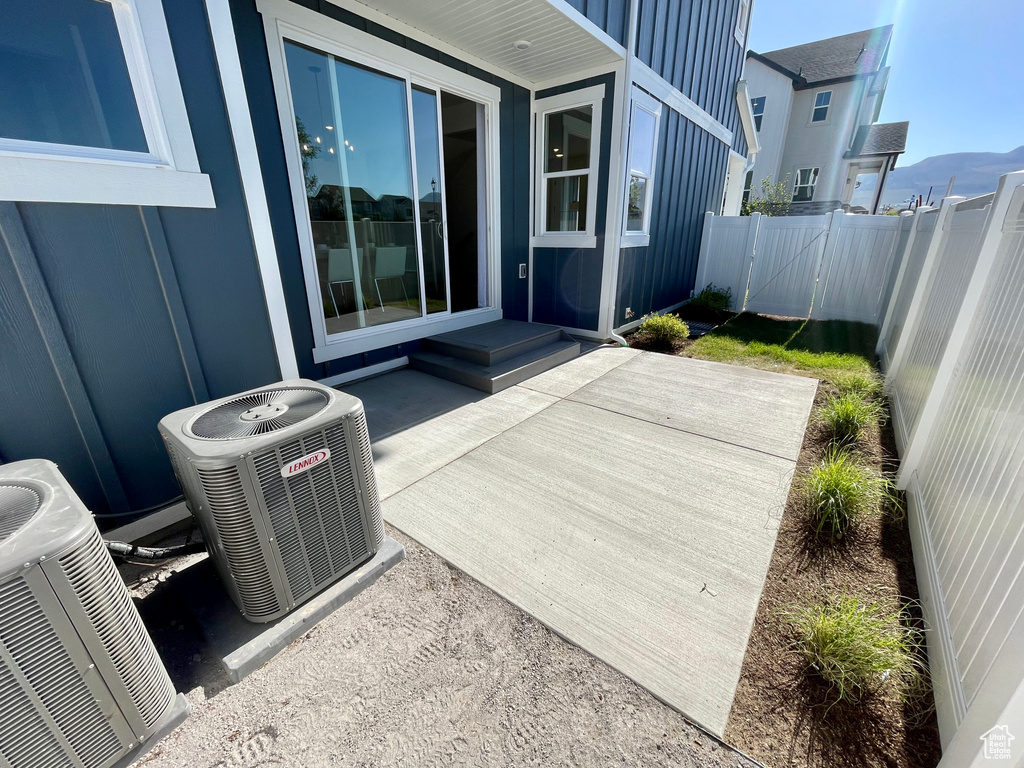 Fenced backyard with central AC unit and a patio
