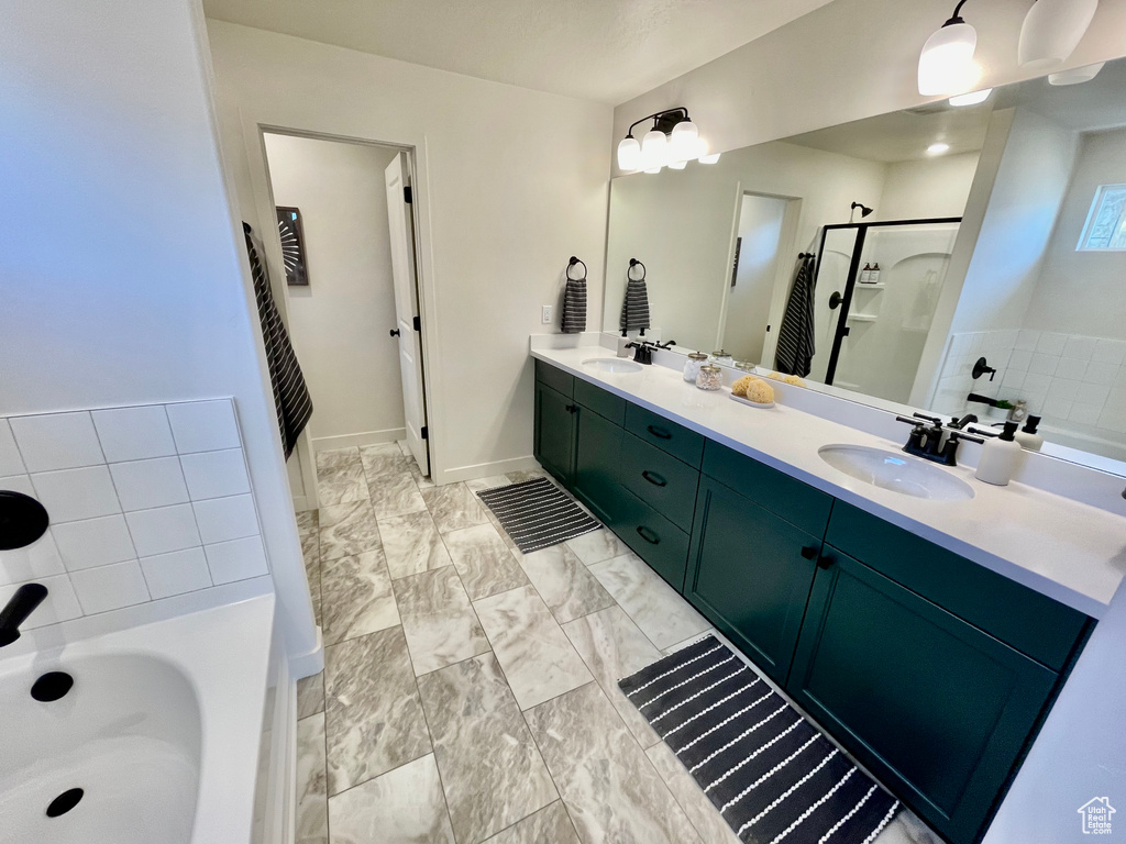Bathroom featuring a garden tub, double vanity, a stall shower, and marble finish floors