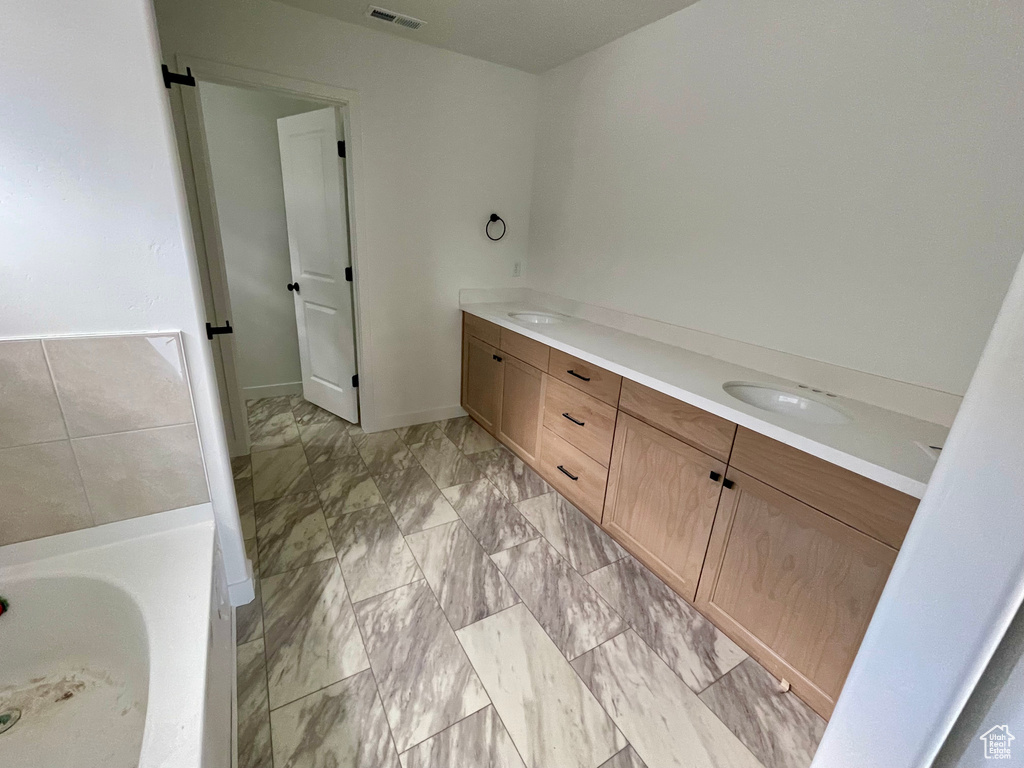 Bathroom featuring double vanity and a tub