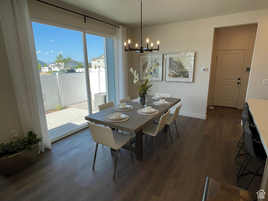 Dining area featuring a chandelier, dark wood-style flooring, and baseboards