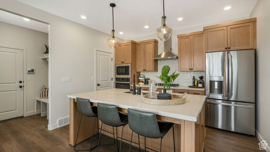 Kitchen featuring stainless steel appliances, dark wood-style flooring, light countertops, wall chimney exhaust hood, and recessed lighting