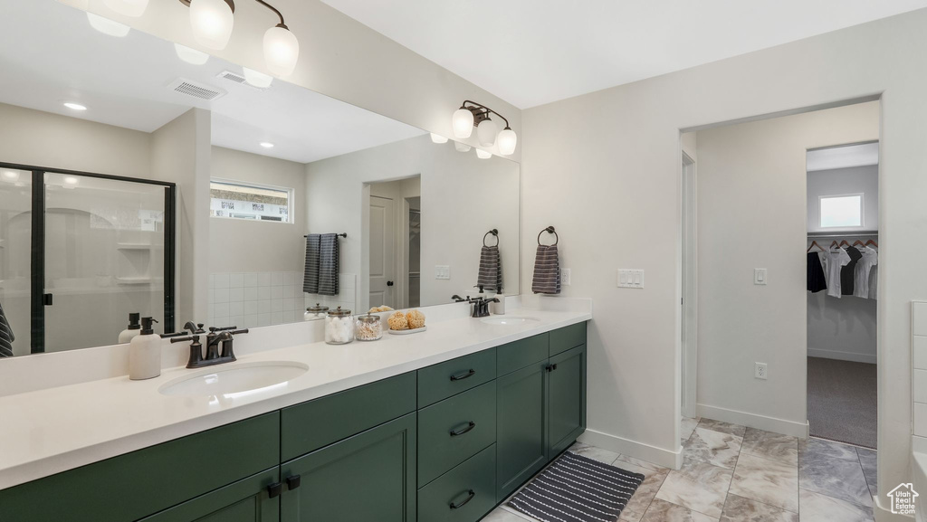Bathroom featuring plenty of natural light, a walk in closet, double vanity, and a shower stall