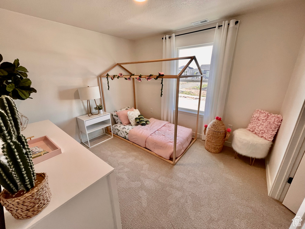 Bedroom with light colored carpet and a textured ceiling
