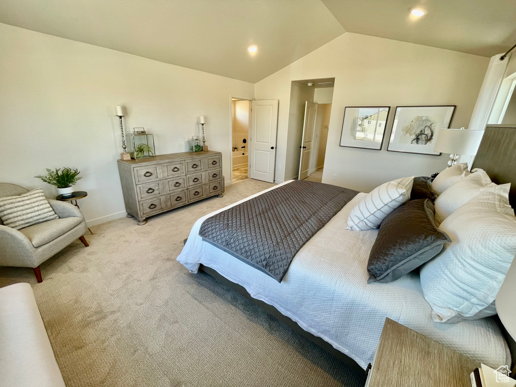 Bedroom with light colored carpet, vaulted ceiling, baseboards, and ensuite bath