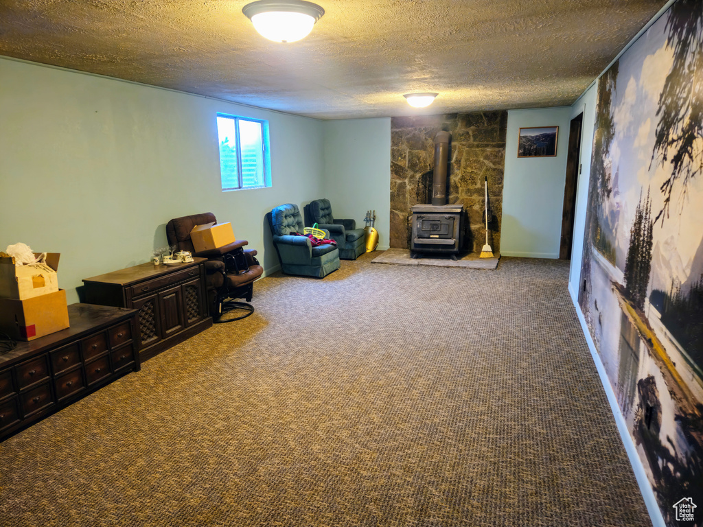 Living area featuring a wood stove, a textured ceiling, and carpet flooring