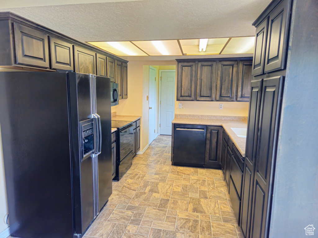 Kitchen featuring black appliances, stone finish floors, and light countertops