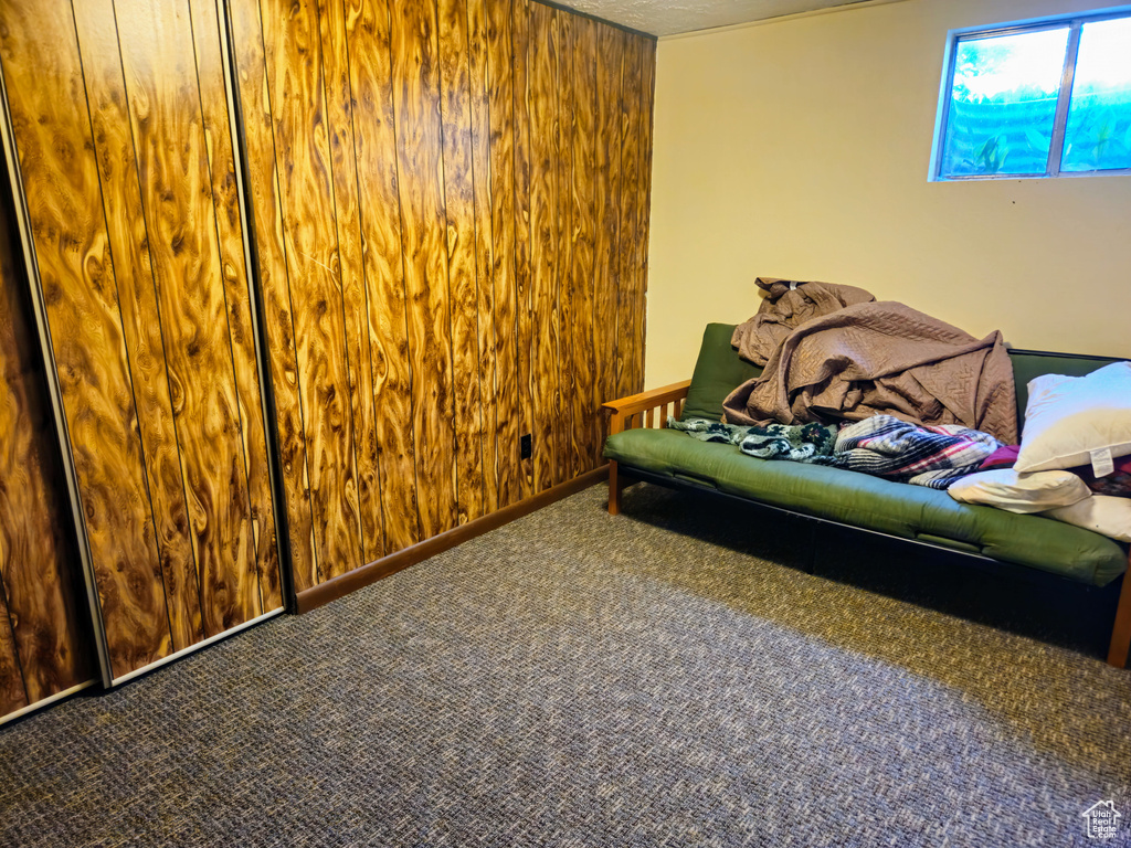 Carpeted bedroom featuring wood walls