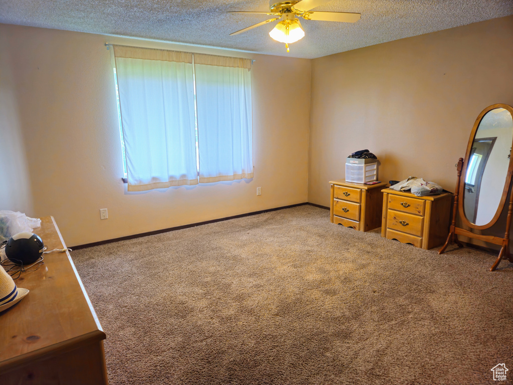 Bedroom with a textured ceiling, carpet floors, baseboards, and a ceiling fan