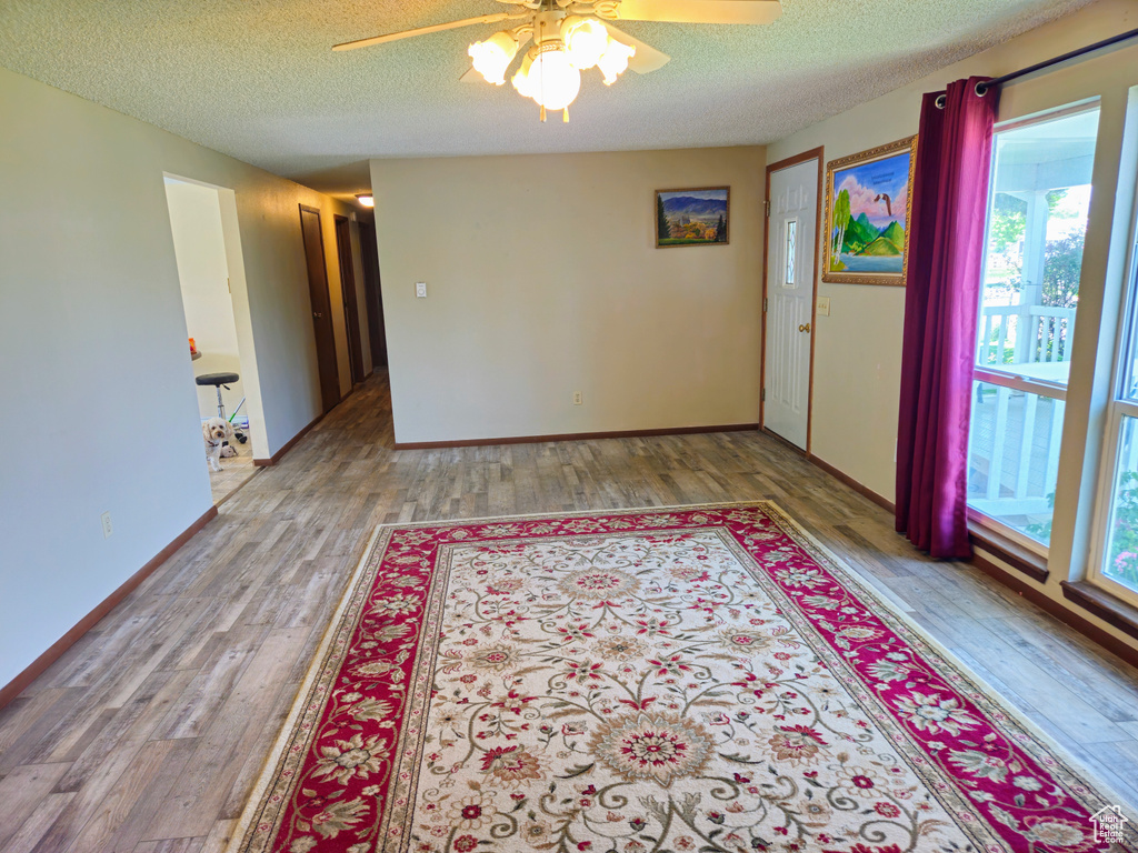 Unfurnished room featuring ceiling fan, a textured ceiling, wood finished floors, and baseboards