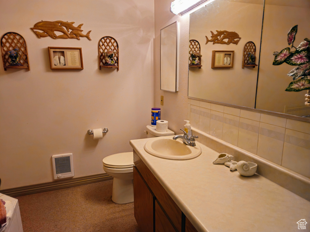 Bathroom featuring heating unit, toilet, and vanity