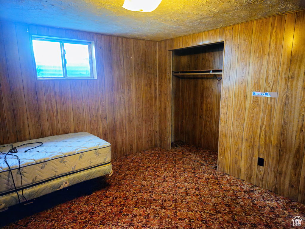Bedroom with wooden walls, carpet flooring, and a closet
