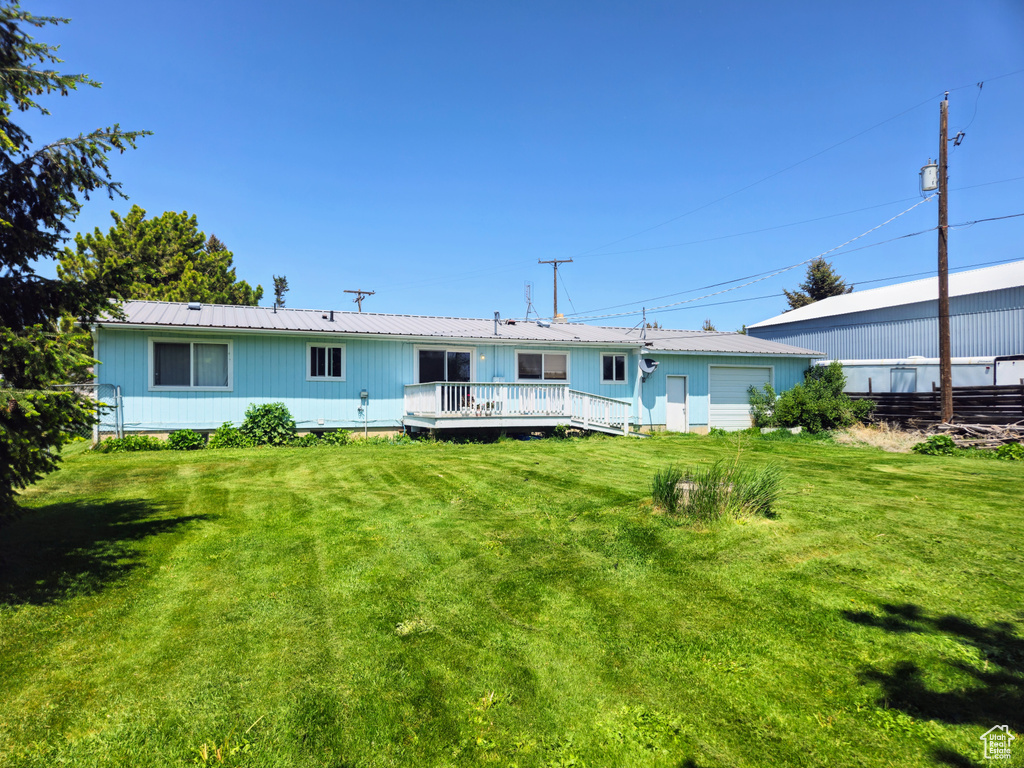 Rear view of house featuring a wooden deck, metal roof, and a yard