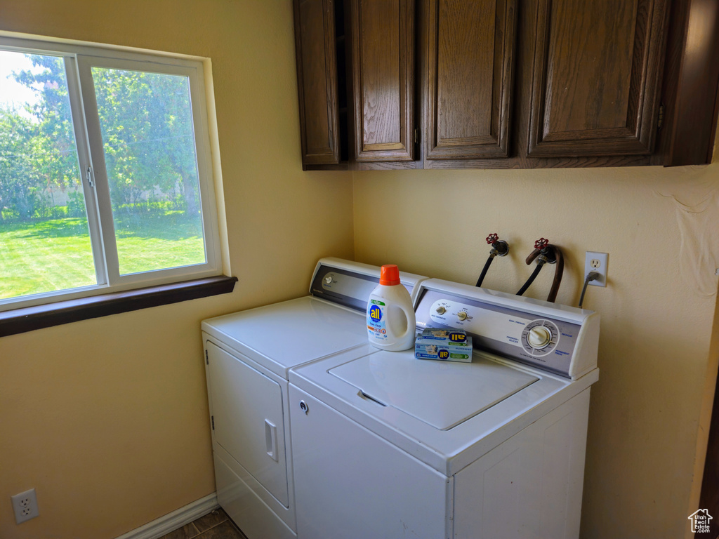 Laundry room with washing machine and dryer, cabinet space, plenty of natural light, and baseboards
