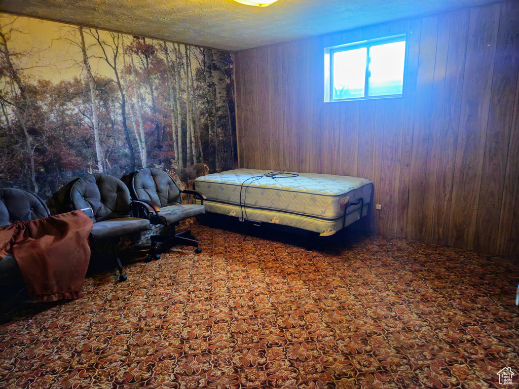 Carpeted bedroom featuring wood walls and a textured ceiling