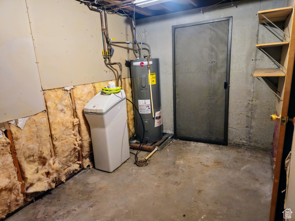 Unfinished below grade area featuring water heater and a water softener system