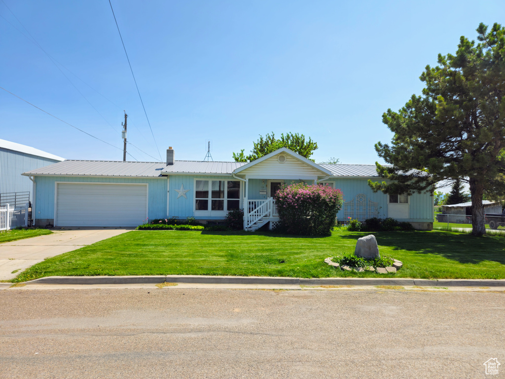 Ranch-style house with an attached garage, a chimney, concrete driveway, and a front lawn